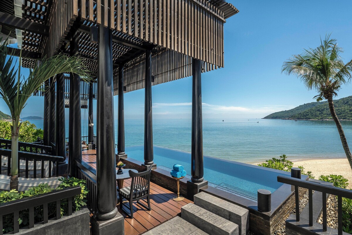 A resort with a pool, outdoor seating, and a view of the sea.