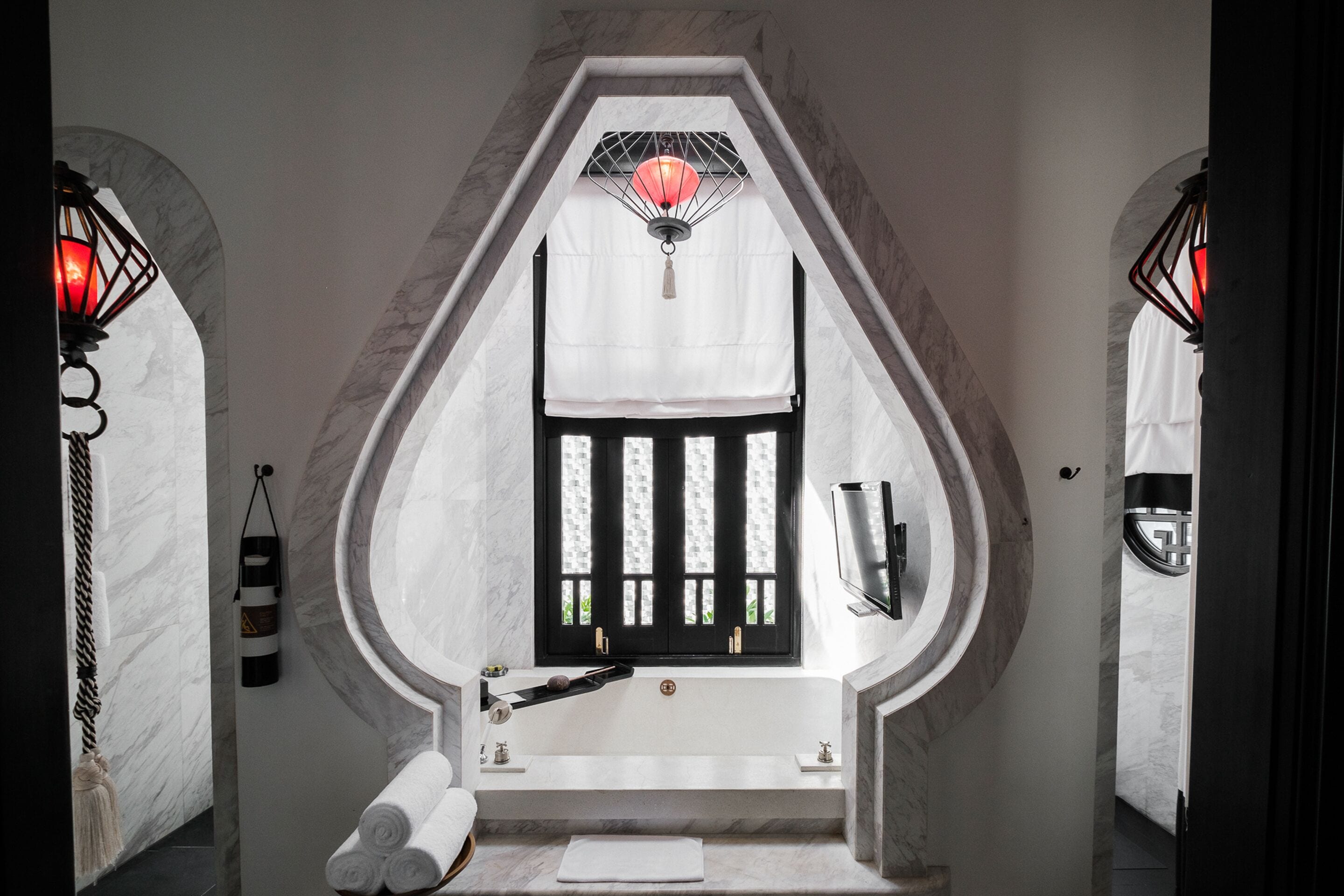 A bathroom with a freestanding bathtub, a towel rack, and a window with a decorative lantern.