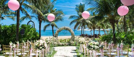 A beach wedding setup with a floral arch and chairs arranged for guests.