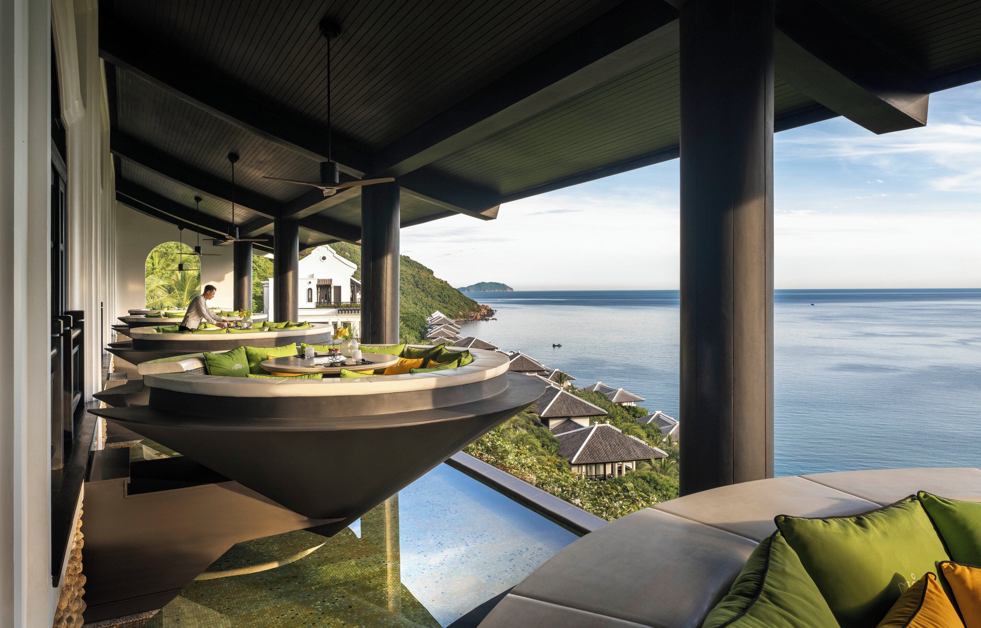 A modern outdoor seating area with a view of the sea, featuring a unique circular table and tiered seating.
