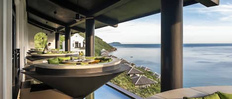 A modern outdoor seating area with a view of the sea, featuring a unique circular table and tiered seating.