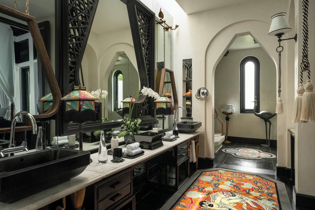 A luxurious bathroom with a large black sink, multiple mirrors, a decorative rug, and a unique ceiling design.