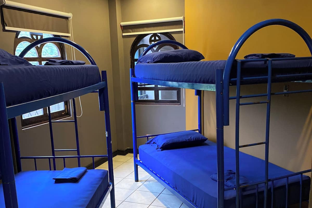 Um quarto de dormitório com beliches, uma janela com vista e um ar-condicionado.