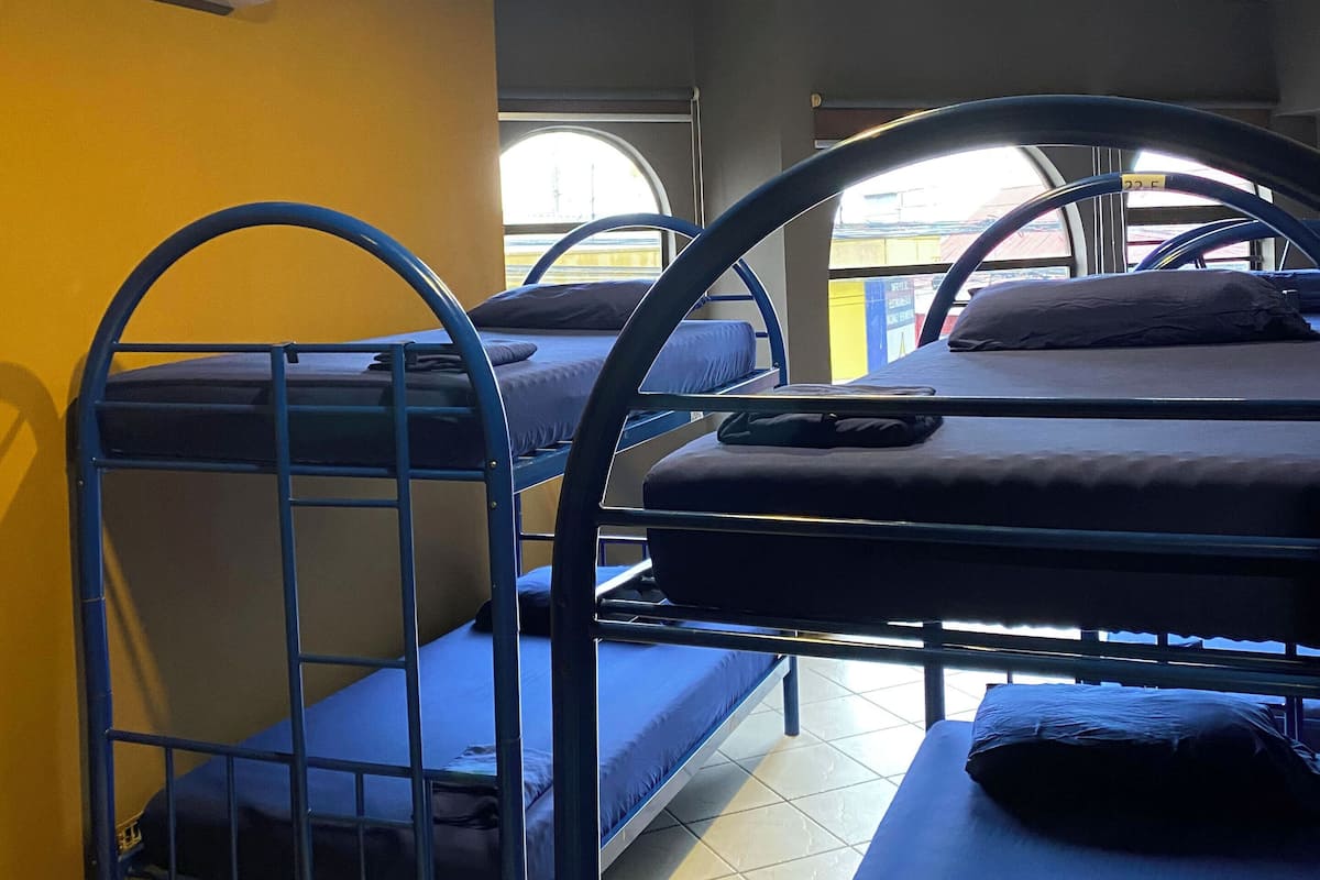 Quarto em dormitório com beliches, ar condicionado e janela com vista.