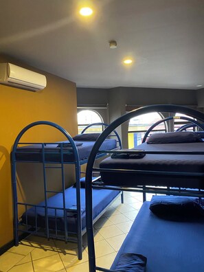 Een slaapzaal met stapelbedden, een airconditioner en een raam met uitzicht.