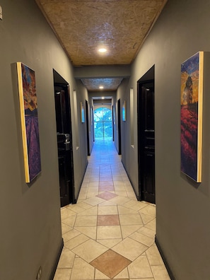 A hallway with a tiled floor, dark walls, and artwork on the sides.