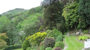 Un jardín exuberante con un sendero sinuoso, bancos y un muro de piedra.