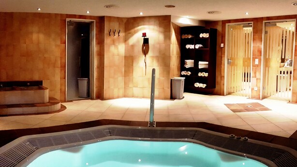 A spa area with a hot tub, seating, and a towel rack. - Europa Annex (Saas-Fee)