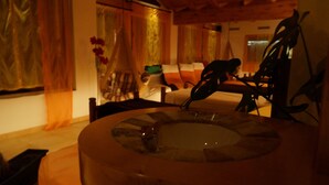 A room with a circular wooden table, a chair, a sofa, and a window with curtains. - Europa Annex (Saas-Fee)