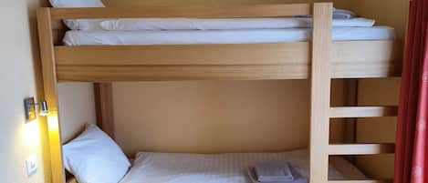 A bunk bed with white bedding and a red curtain.