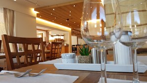 A dining area with wooden chairs, a table set with cutlery, and two wine glasses. - Europa Annex (Saas-Fee)
