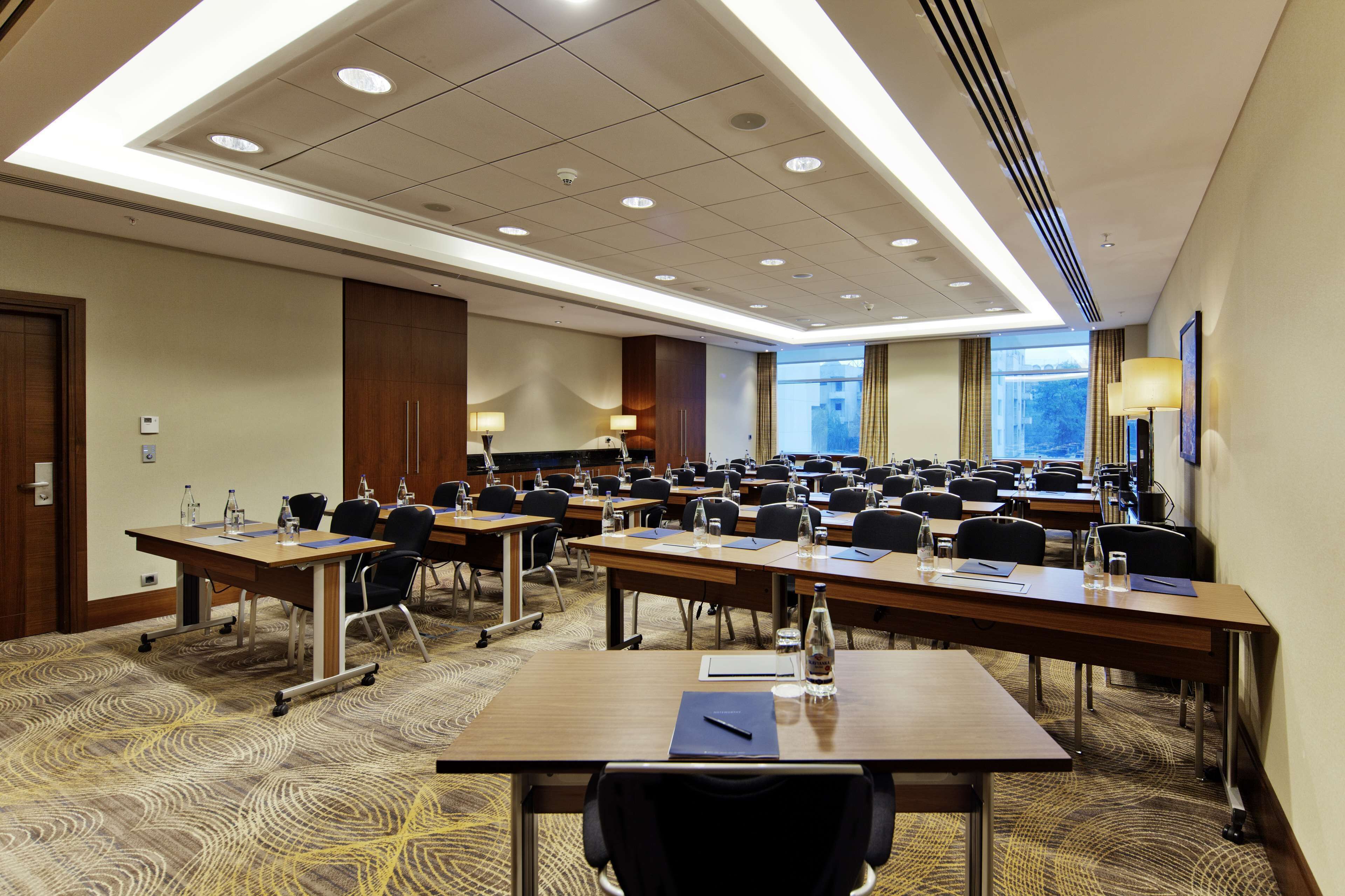A conference room with multiple tables and chairs, equipped with water bottles and notepads.