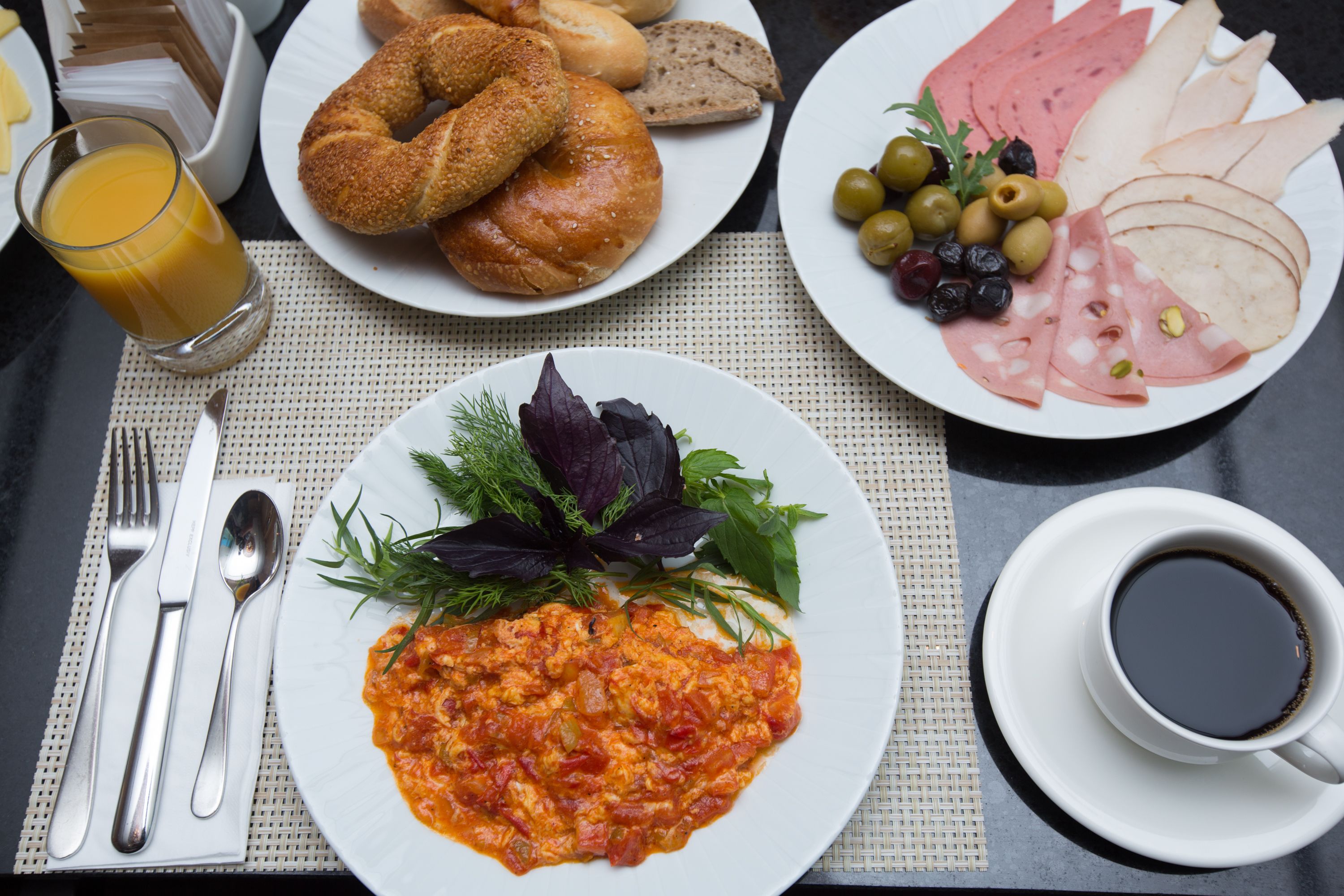 A breakfast setting with plates of food, a glass of orange juice, and a cup of coffee.