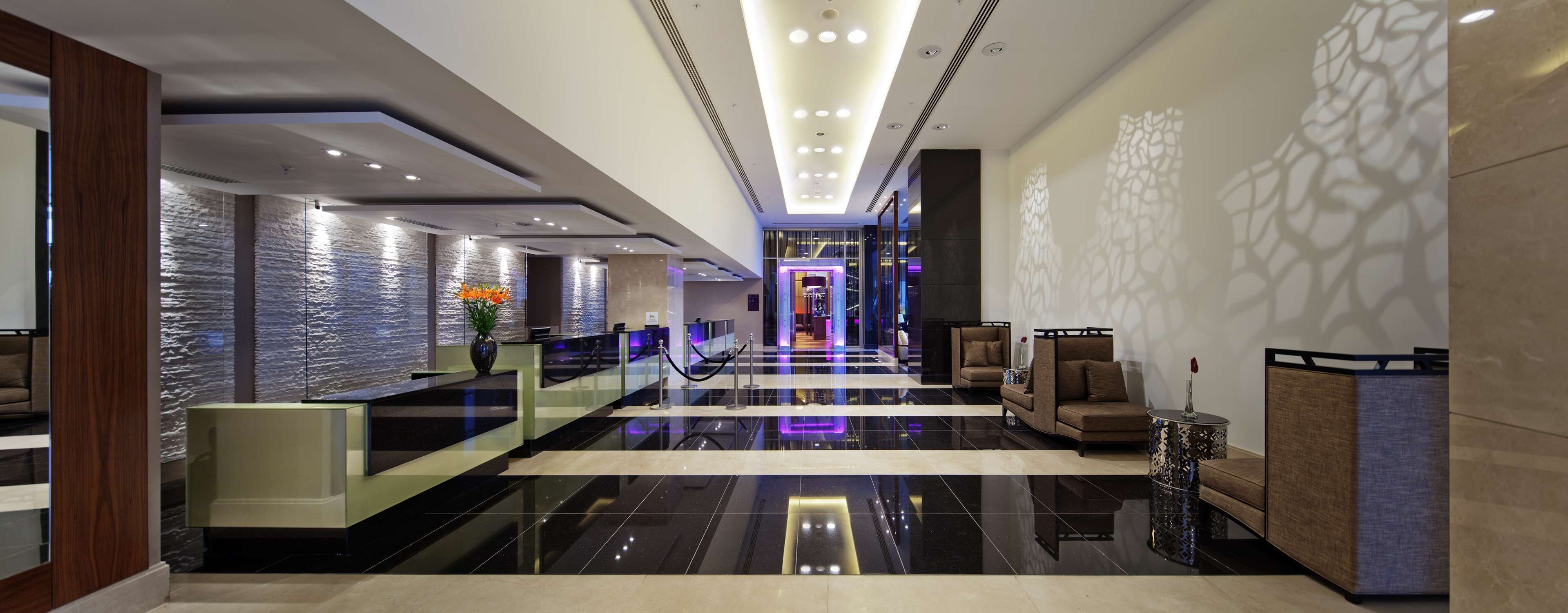 A modern hotel lobby with a reception desk, seating area, and a view into the hotel rooms.