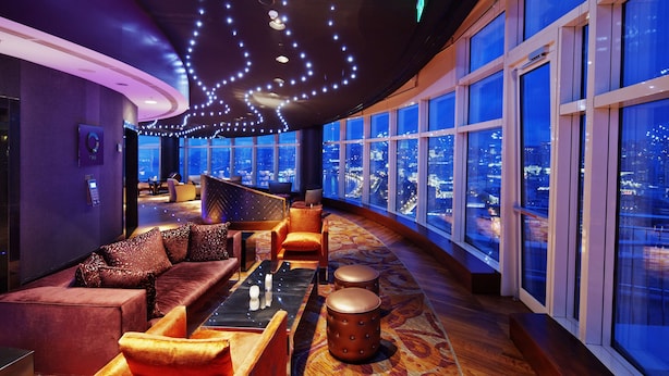A modern lounge with a curved ceiling, plush seating, and large windows offering city views. - Hilton Baku (Baku)