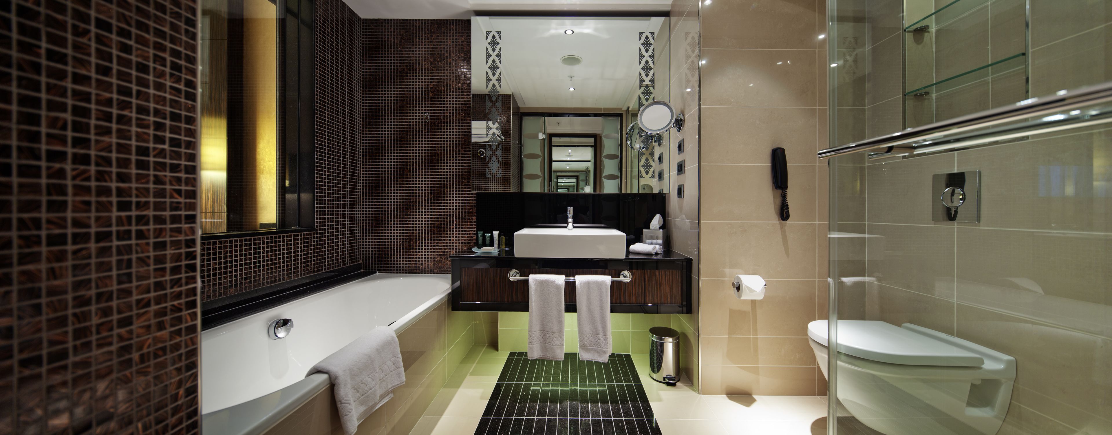 A modern bathroom with a bathtub, a vanity with a mirror, and a toilet.