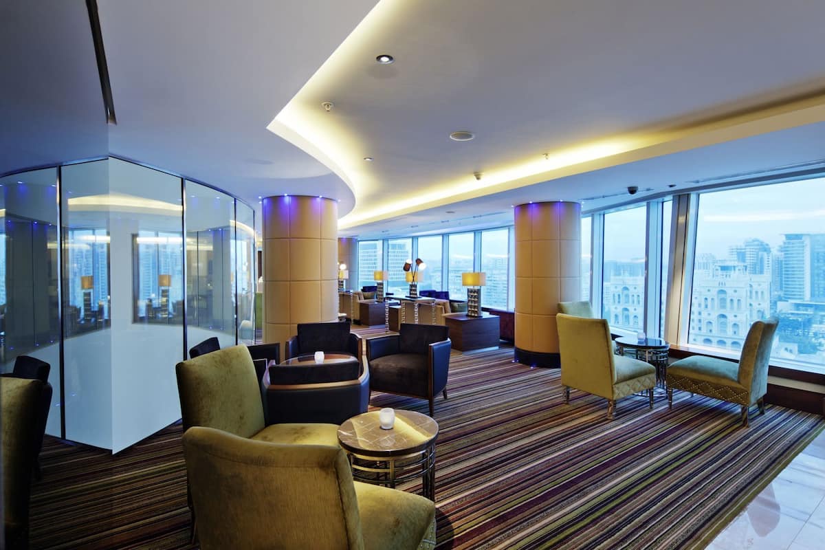 Un moderno vestíbulo de hotel con vistas panorámicas de la ciudad, un separador de vidrio y diversas opciones de asientos.