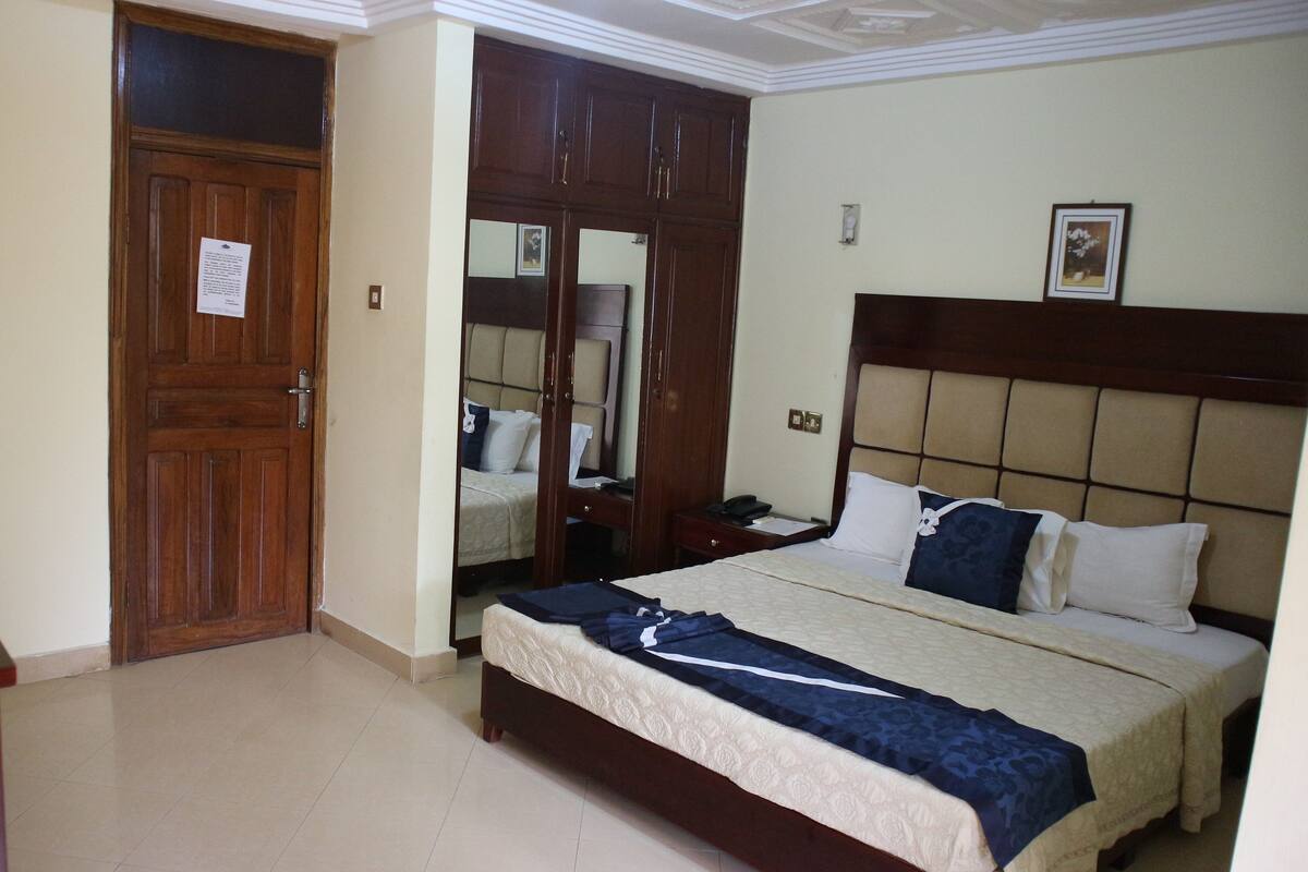 A hotel room with a bed, a desk, a television, and a wardrobe.