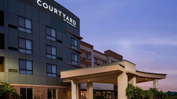Un hôtel Courtyard by Marriott doté d’une façade moderne, de grandes fenêtres et d’un espace d’entrée abrité.