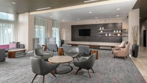 Un salon moderne doté d’un téléviseur à écran plat, de sièges confortables et d’une étagère décorative.