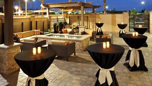 Un espace extérieur aménagé avec un patio, des sièges, un foyer et des tables décorées de bougies.