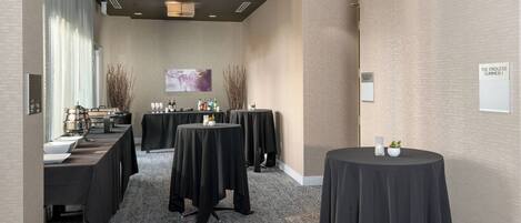 A conference room with multiple tables, a large window with curtains, a wall-mounted painting, and a sign reading "THE ENDLESS SUMMER I".