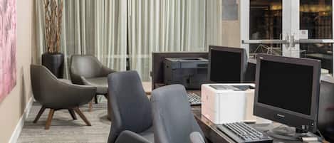 A modern office space with ergonomic chairs, a desktop computer, monitors, and a printer.