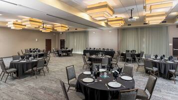 A conference room with round tables, chairs, and a projector screen.