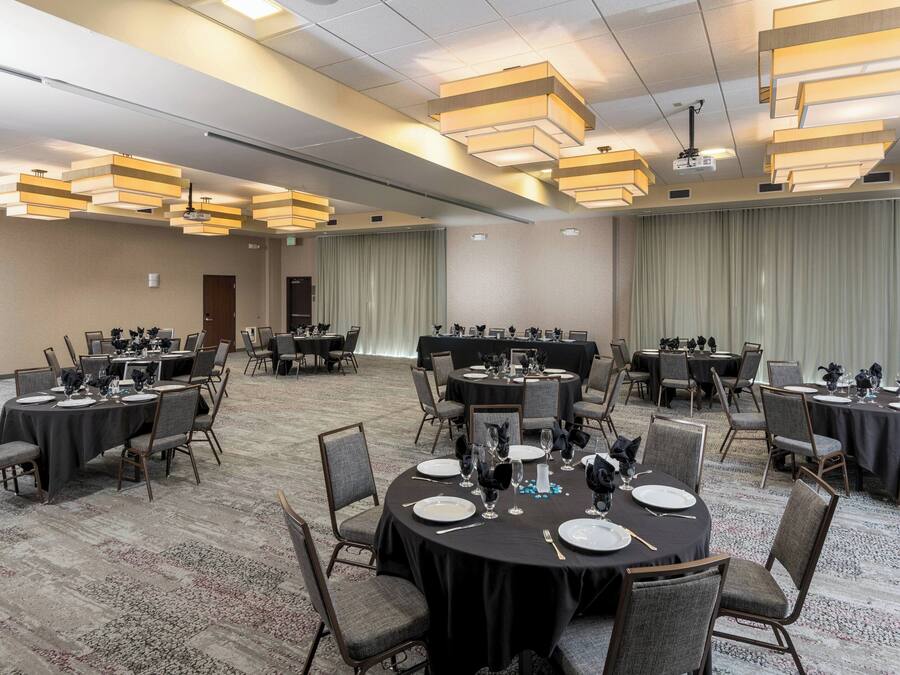 A conference room with round tables, chairs, and a projector screen.