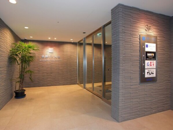 A reception area with a modern design, featuring a reception desk, a potted plant, and a wall-mounted information board.