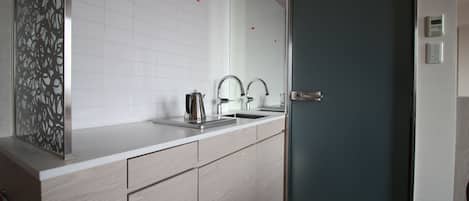 A modern bathroom with a large mirror, a sink, and a door.