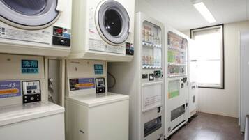 Un cuarto de lavandería con varias lavadoras y secadoras, una máquina expendedora y un dispensador automático de detergente.