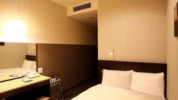 Habitación de hotel con cama, escritorio y silla. Hay un espejo en la pared y una ventana.