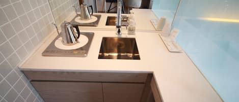 Una cocina moderna con un lavamanos de acero inoxidable, cafetera y horno empotrado.