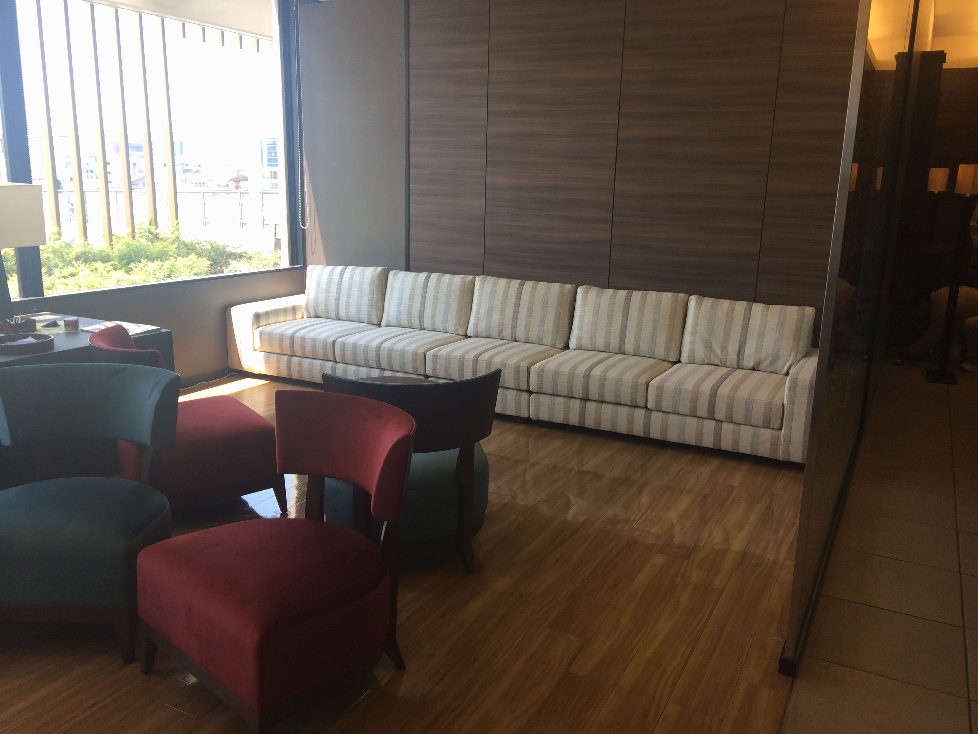 Ein modernes Wohnzimmer mit einem gestreiften Sofa, roten und blauen Sesseln und einem Holzboden.