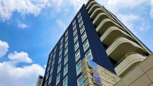 A tall hotel building with multiple balconies and a clear sky. - Meitetsu Inn Nagoya Sakuradori (Nagoya)