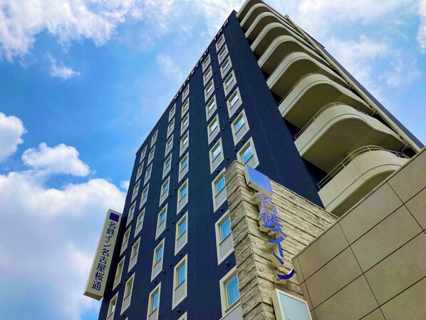 A tall hotel building with multiple balconies and a clear sky. - Meitetsu Inn Nagoya Sakuradori (Nagoya)