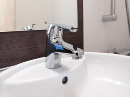 A modern bathroom sink with a chrome faucet and a mirror above it.