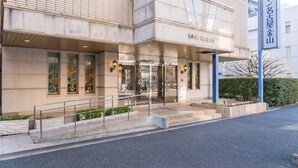 A hotel entrance with a glass door, a metal railing, and a blue sign with Japanese characters. - Meitetsu Inn Nagoya Kanayama (Nagoya)