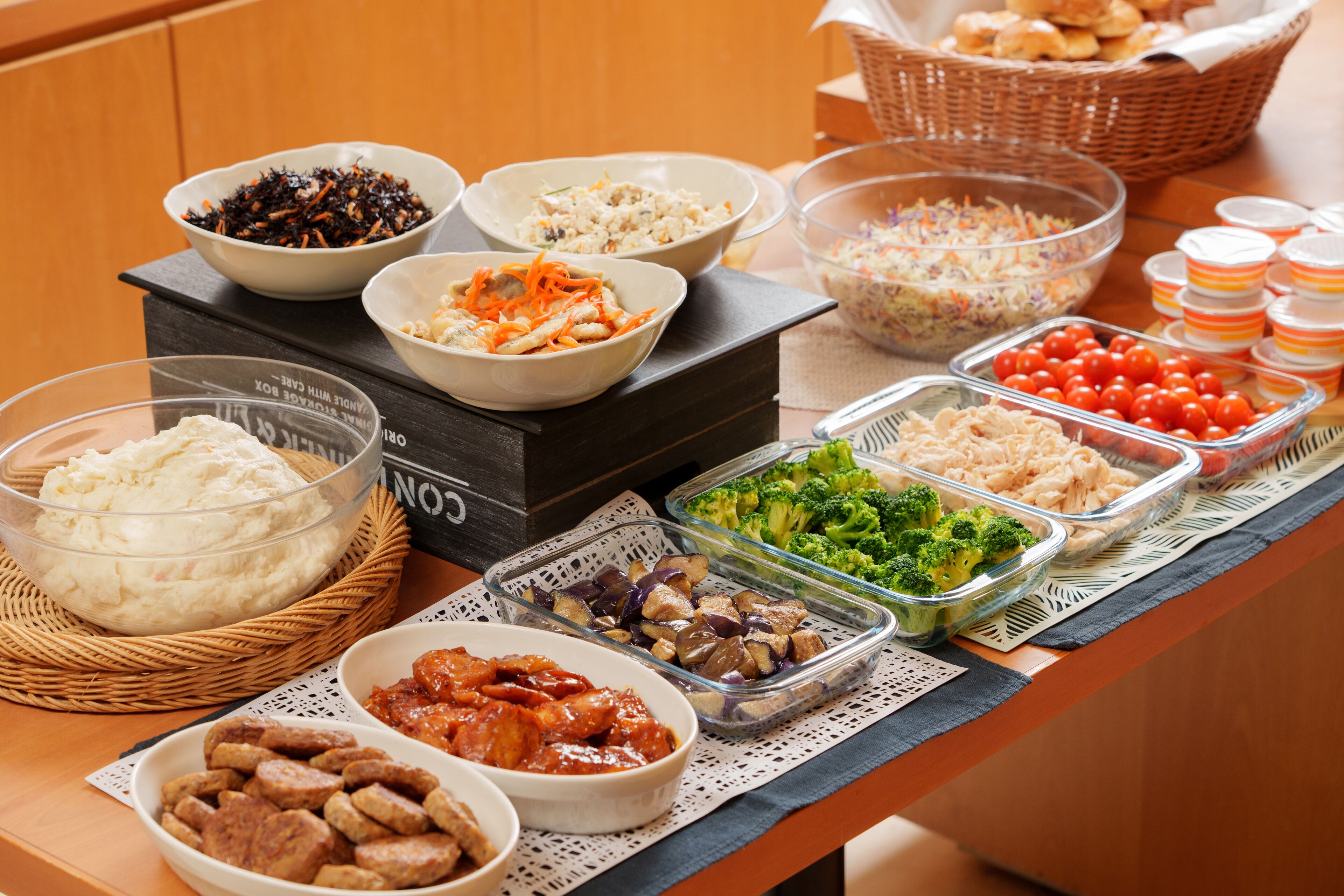 Una mesa de buffet con diversos platos, incluyendo puré de papas, ensalada de col y pasta.