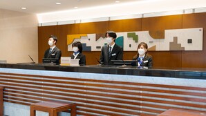 A reception desk with four staff members, a marble counter, and wooden benches. - Meitetsu Inn Nagoya Kanayama (Nagoya)