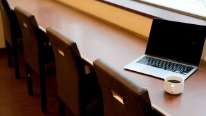 A wooden table with a laptop and a white mug.