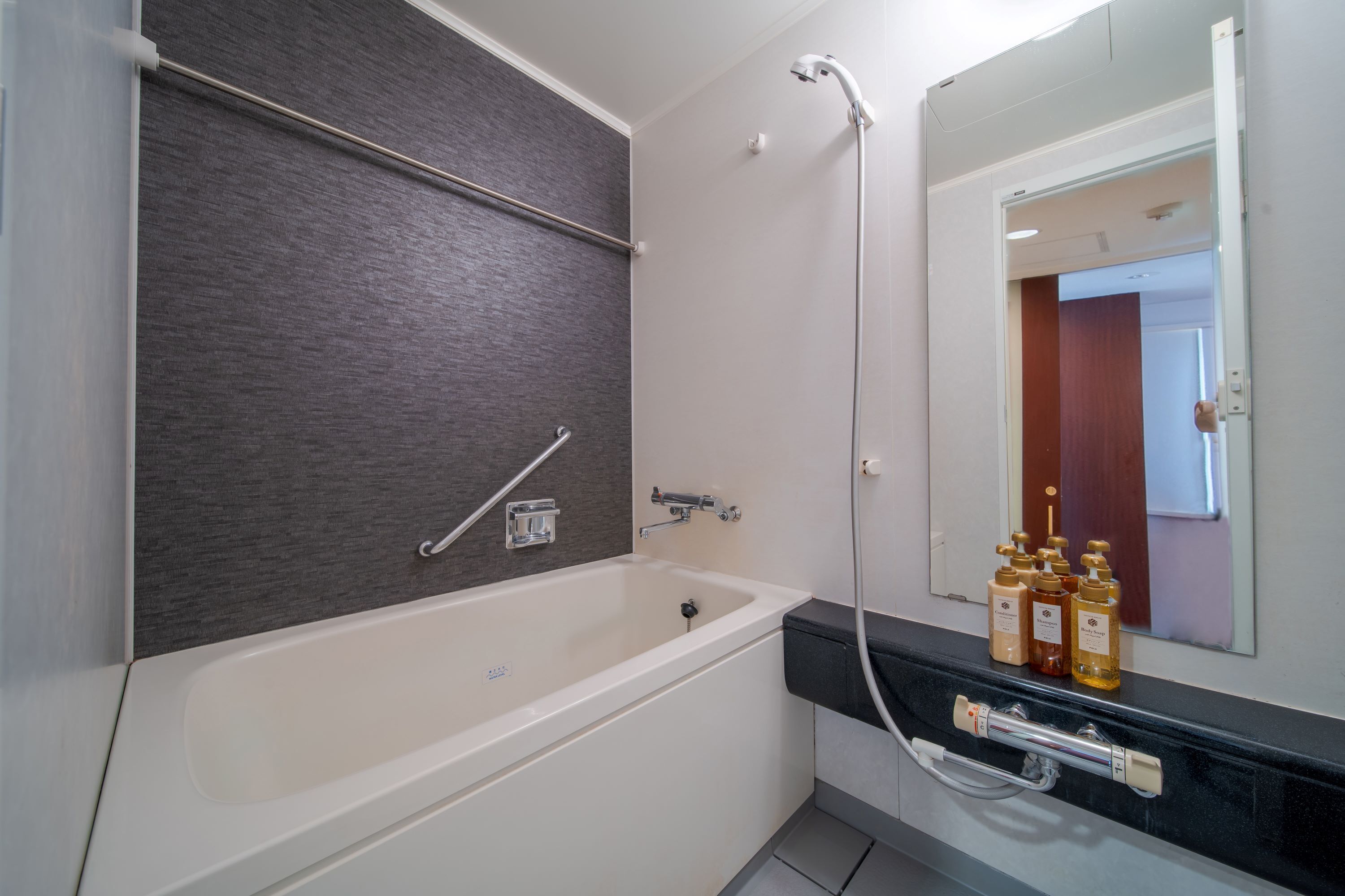 A modern bathroom with a bathtub, a shower, and a vanity with toiletries.