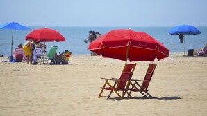 Uma praia com guarda-sóis vermelhos e cadeiras de praia.