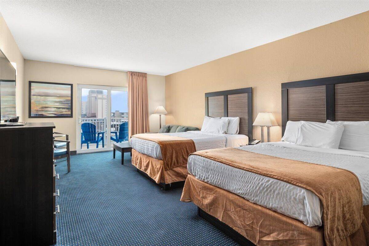 A hotel room with two beds, a desk, and a chair.