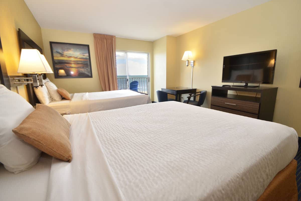 A hotel room with two beds, a desk, a television, and a painting on the wall.