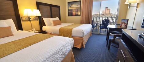 A hotel room with two beds, a desk, a chair, a TV, and a balcony with a city view.