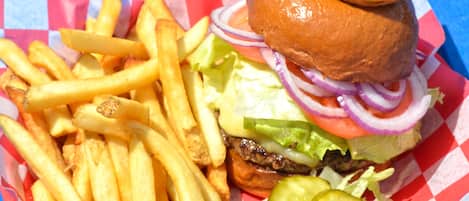 A burger with fries and pickles on a red and white checkered paper.