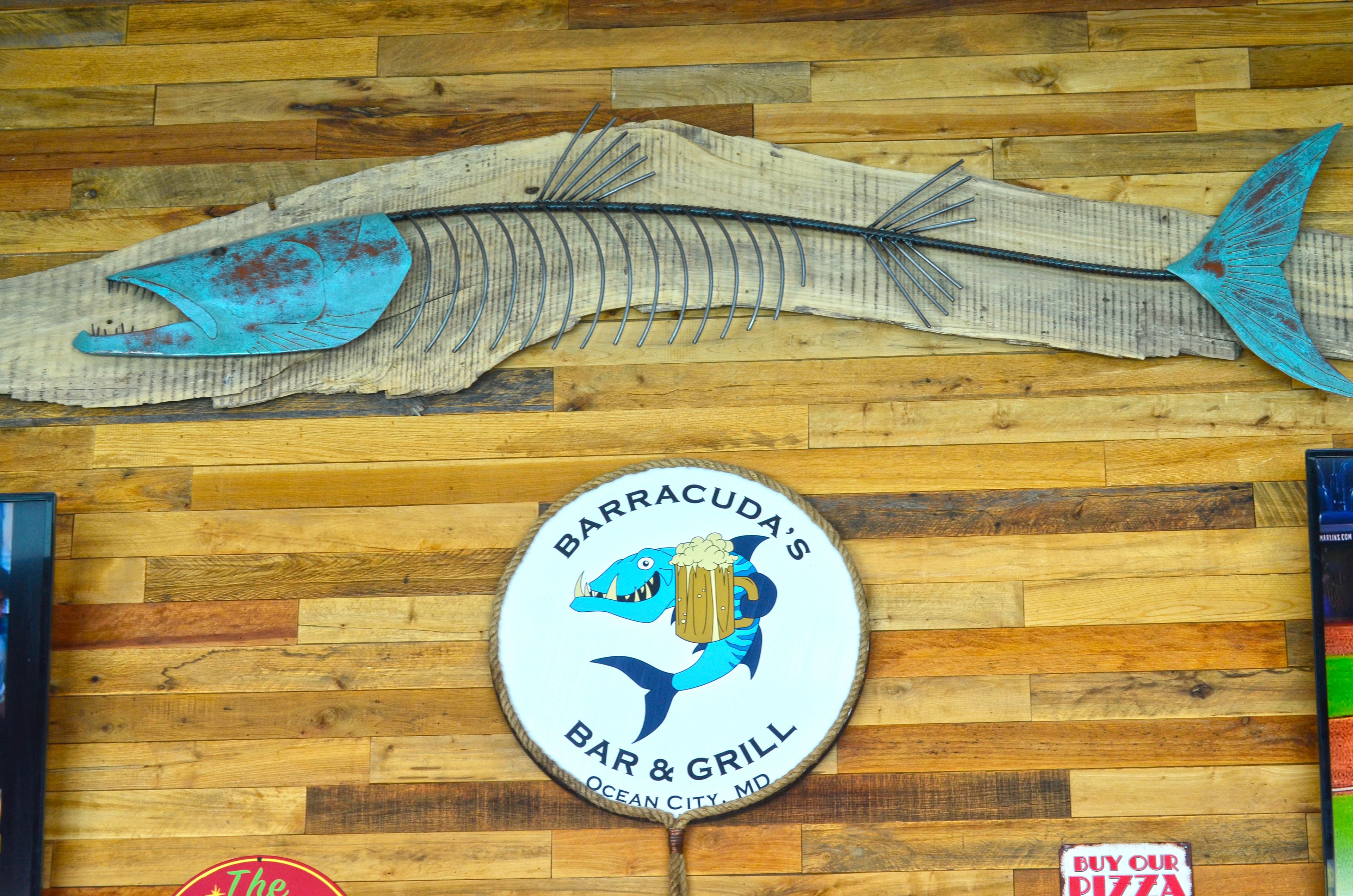 A wooden wall with a fish skeleton decoration and a circular sign for Barracuda's Bar & Grill.