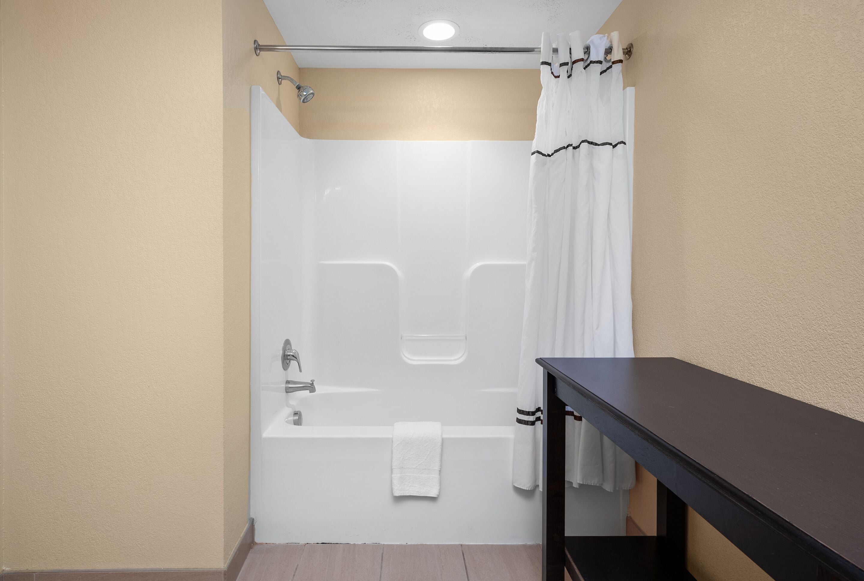 A bathroom with a bathtub, a shower curtain, and a towel hanging on the wall.